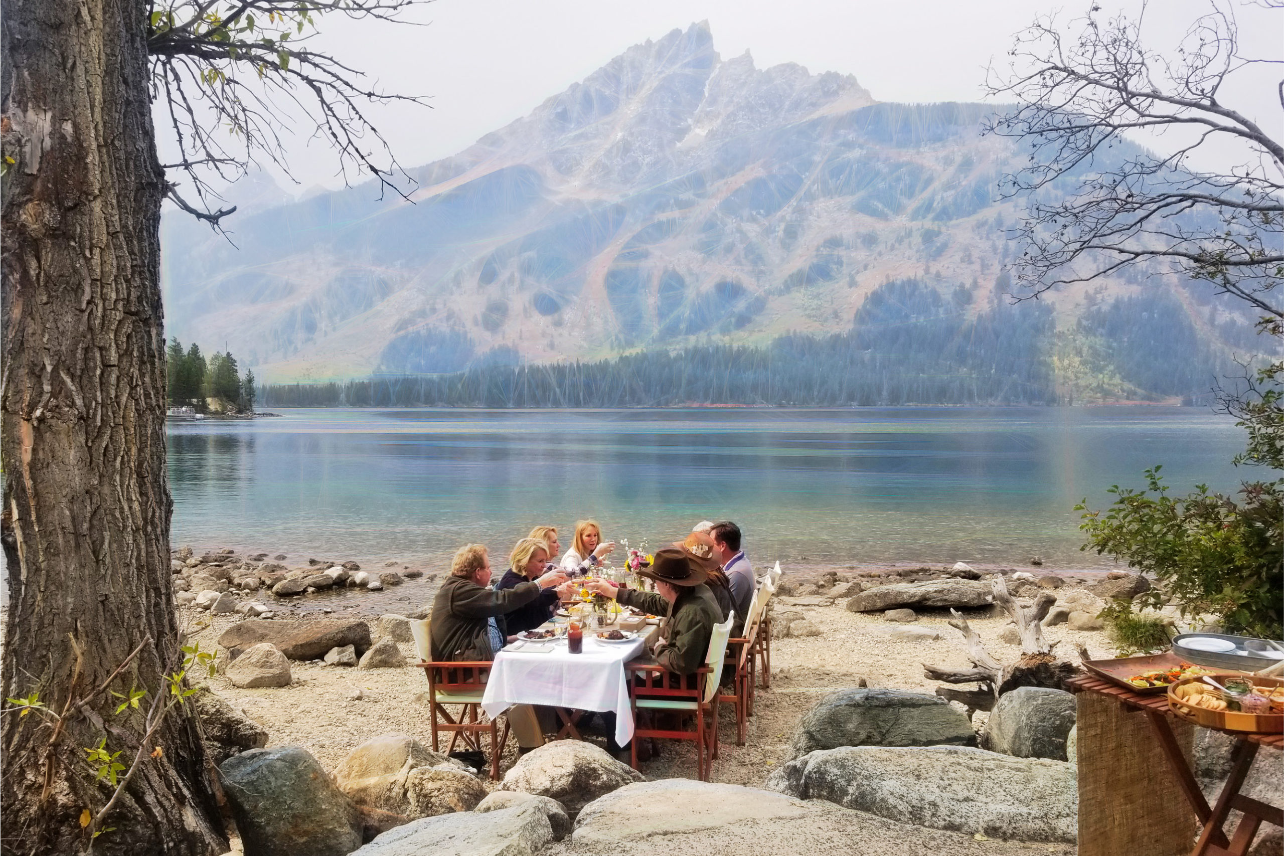 Elevated picnic during a Grand Teton tour by a lakeside with mountain views and outdoor dining setup