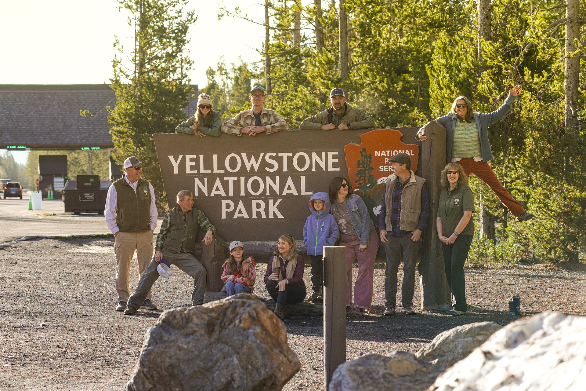 A group having fun around the Yellowstone National Park Entrance sign