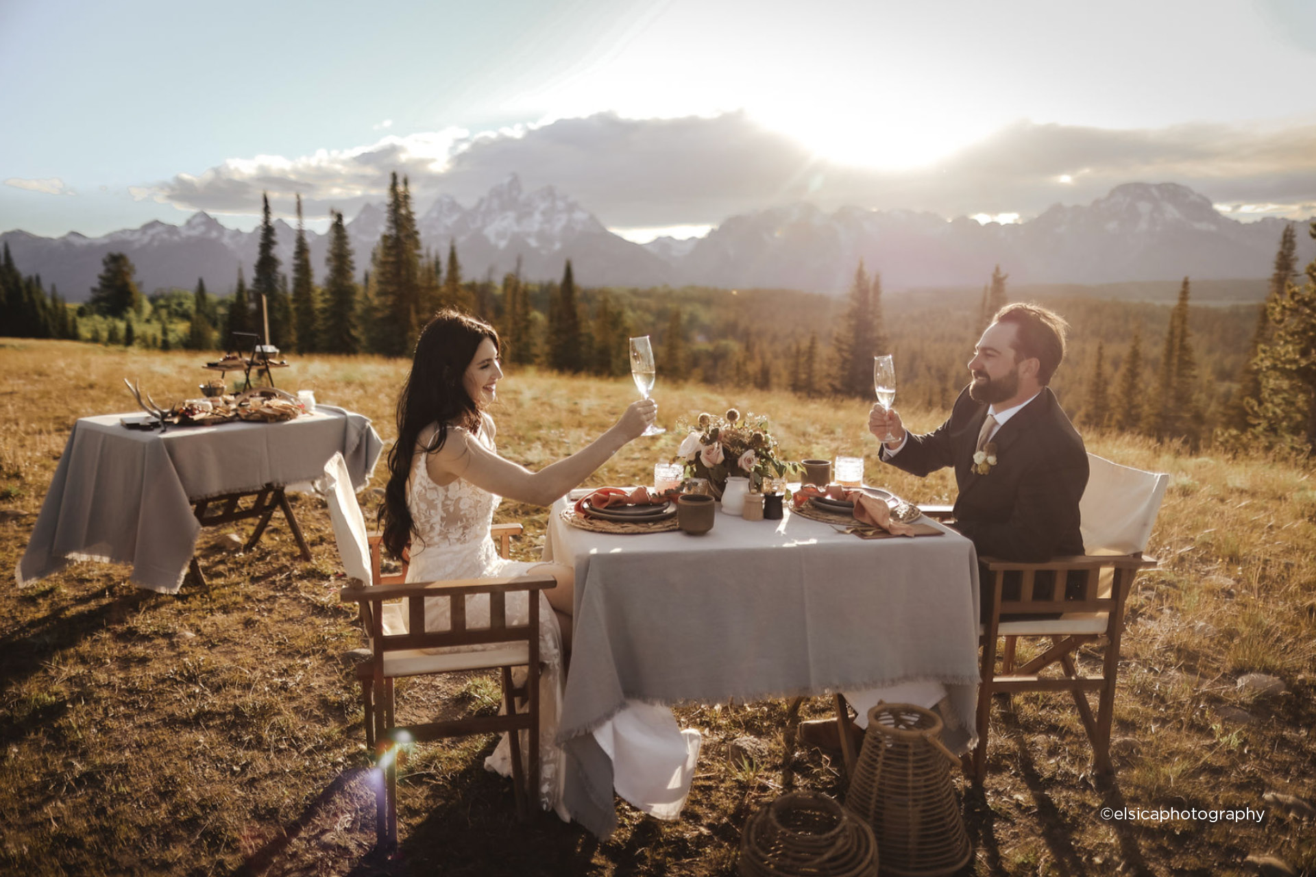 A bride and groom having a champagne toast in front of a Teton sunset
