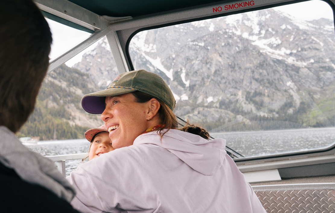 Mom and daughter looking out Jenny Lake boat window to the mountains